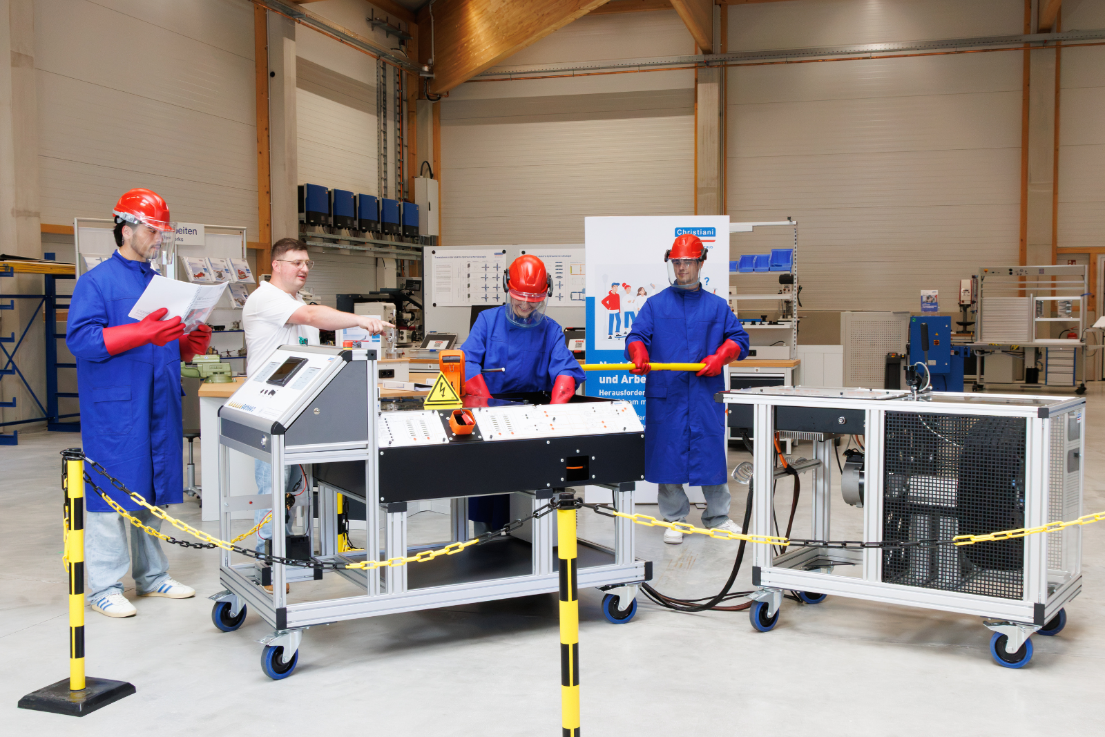 mehrere Personen arbeiten an zwei Übungsstationen für Fahrzeugtechnik