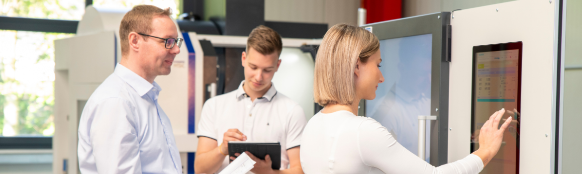 drei Personen arbeiten mit einem Touch-Monitor an einer CNC-Datei